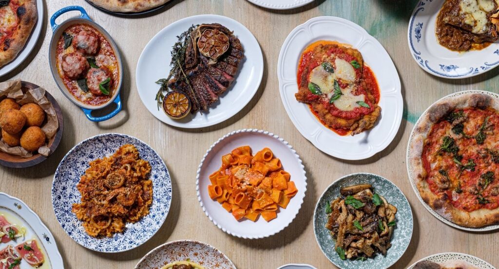 assortment of dishes with pasta with red sauce, chicken parmasean, meatballs, and more from Alla Vita