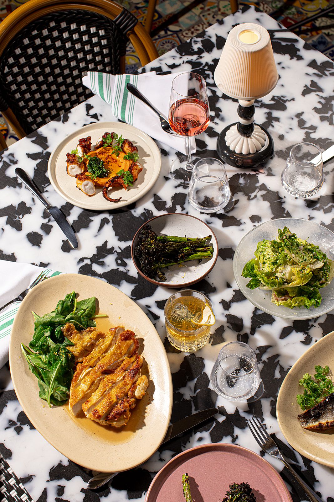 A spread of dishes with wine on a black and white stone table at Bar Issi