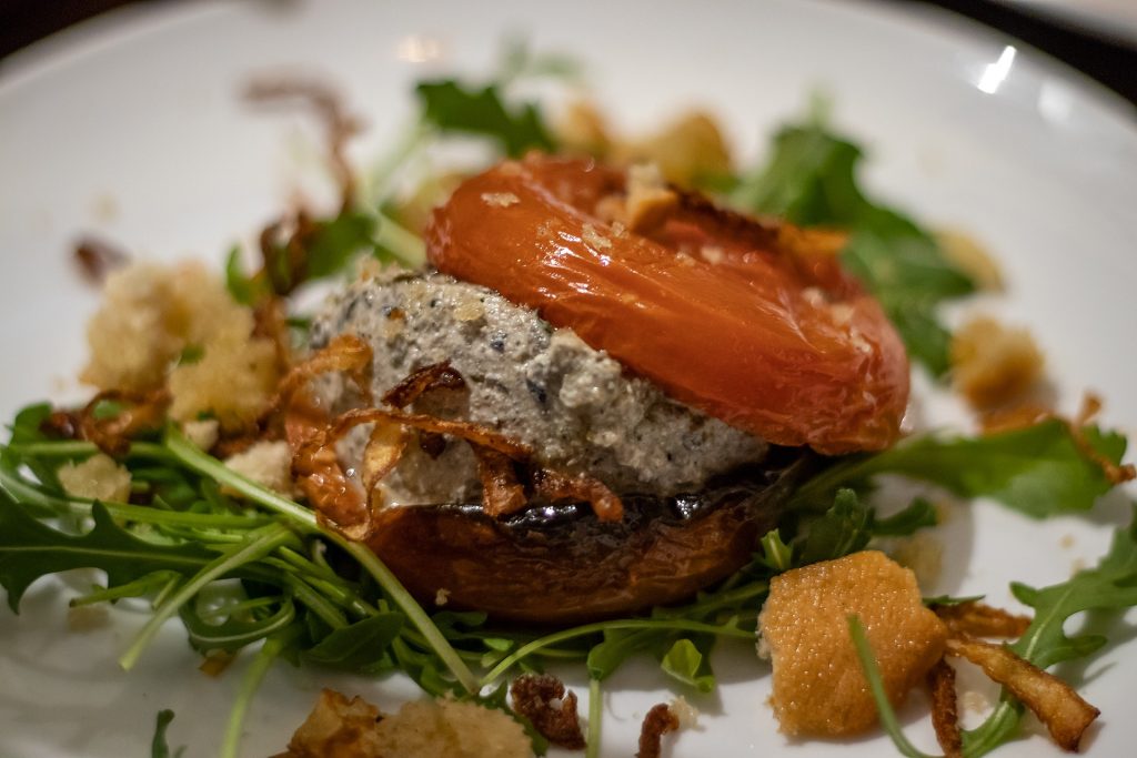 Roast tomato with olive tapenade and ricotta on a plate at Italian restaurant Buonissimo