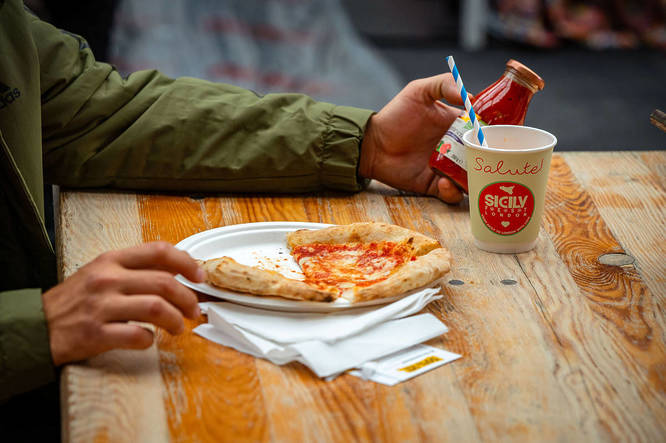 Person eating a pizza at SicilyFEST