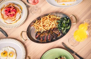 A table with plates full of pancakes, eggs and steak frites