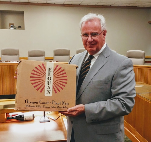 David Gombery holds a case box with the words Elouan, Oregon Coast, Pinot Noir, Willamette Valley, Umpqua Valley, Rogue Valley