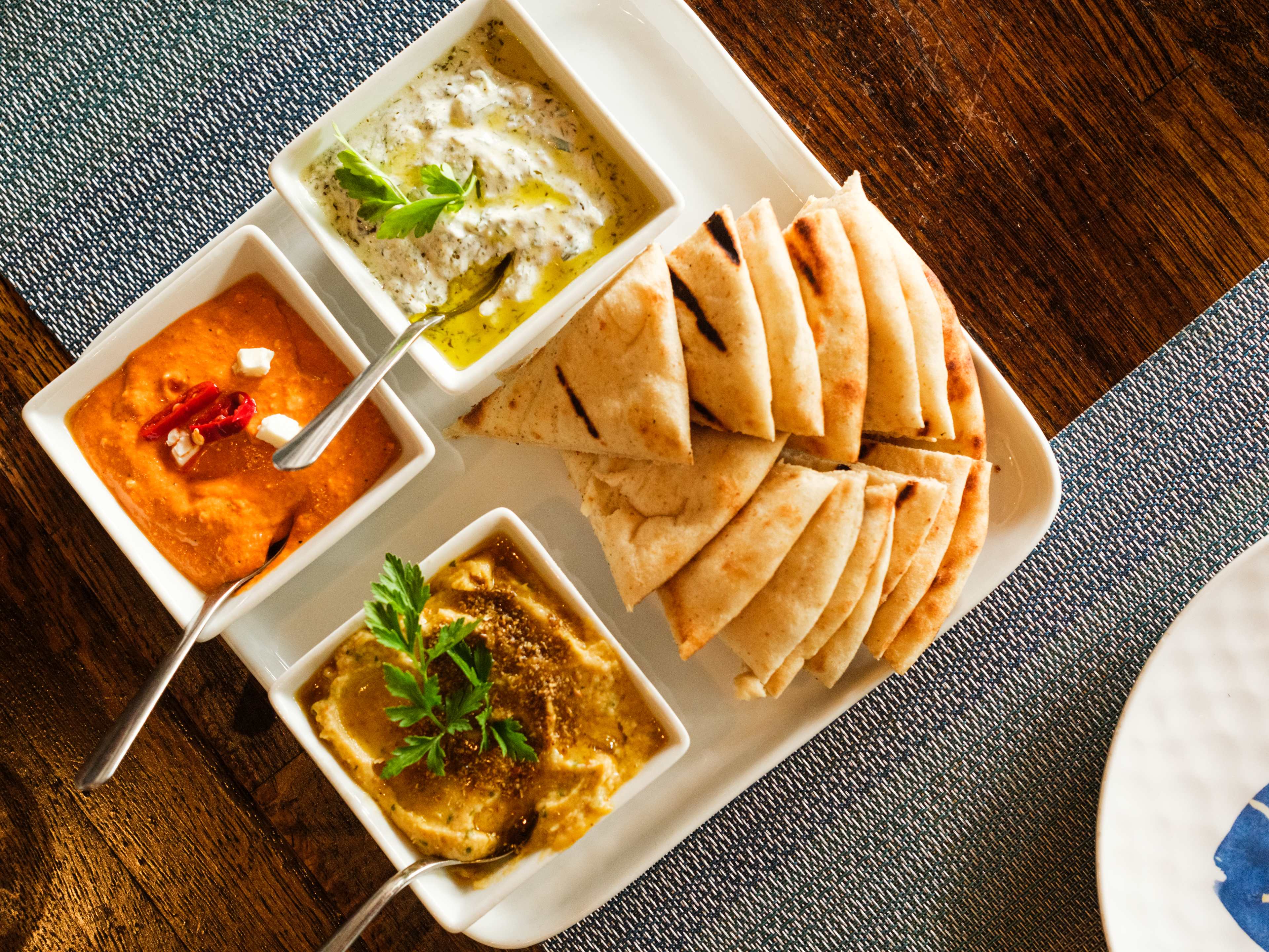 trio of red pepper, hummus, and tzatziki dips and a side of pita bread