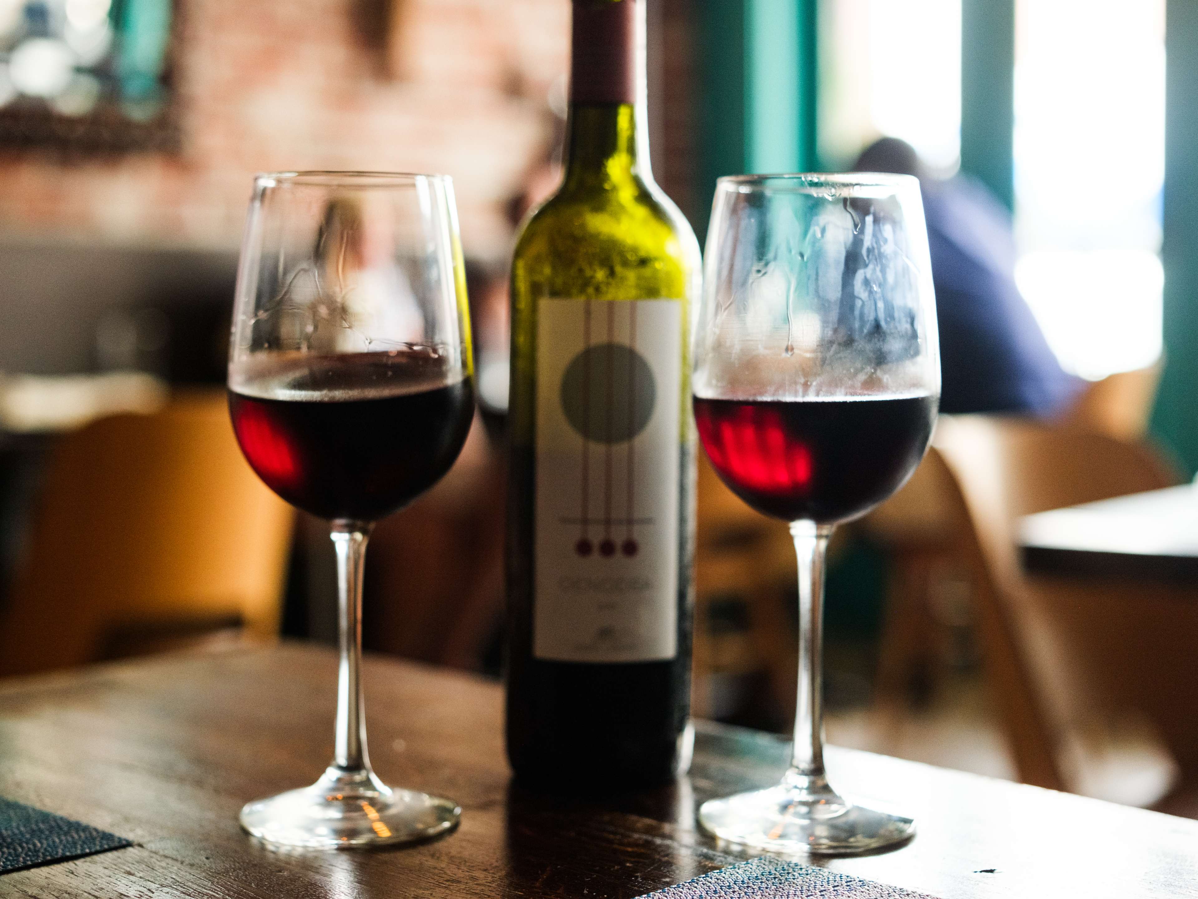 Two glasses of wine and a bottle on a table at Helen Greek Food & Wine.