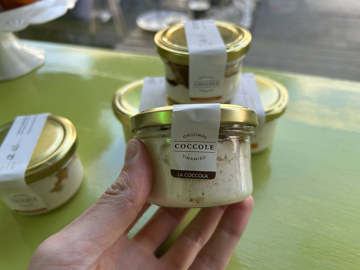 a jar of tiramisu being held up, with others visible in the background