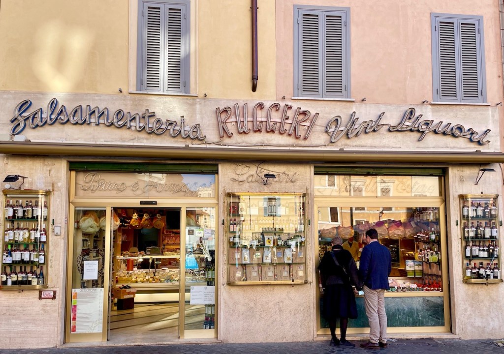Couple stand outside window shopping at Antica Pizzicheria Ruggeri.