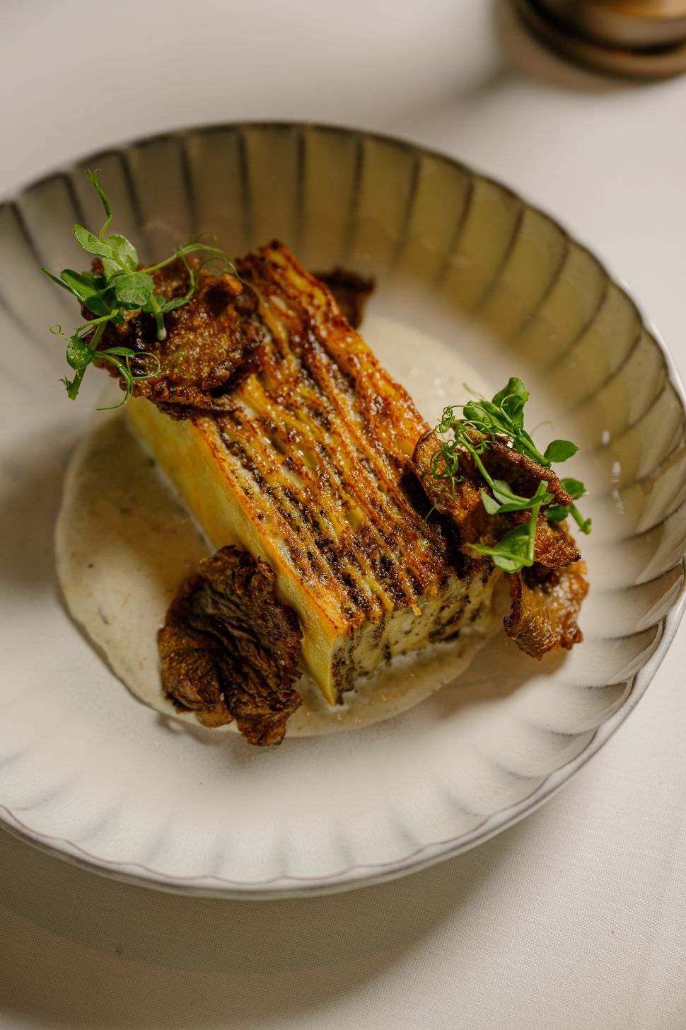 A serving of classic lasagna with layers of pasta, meat, cheese, and sauce, topped with a golden-brown crust, served in a rustic dish.