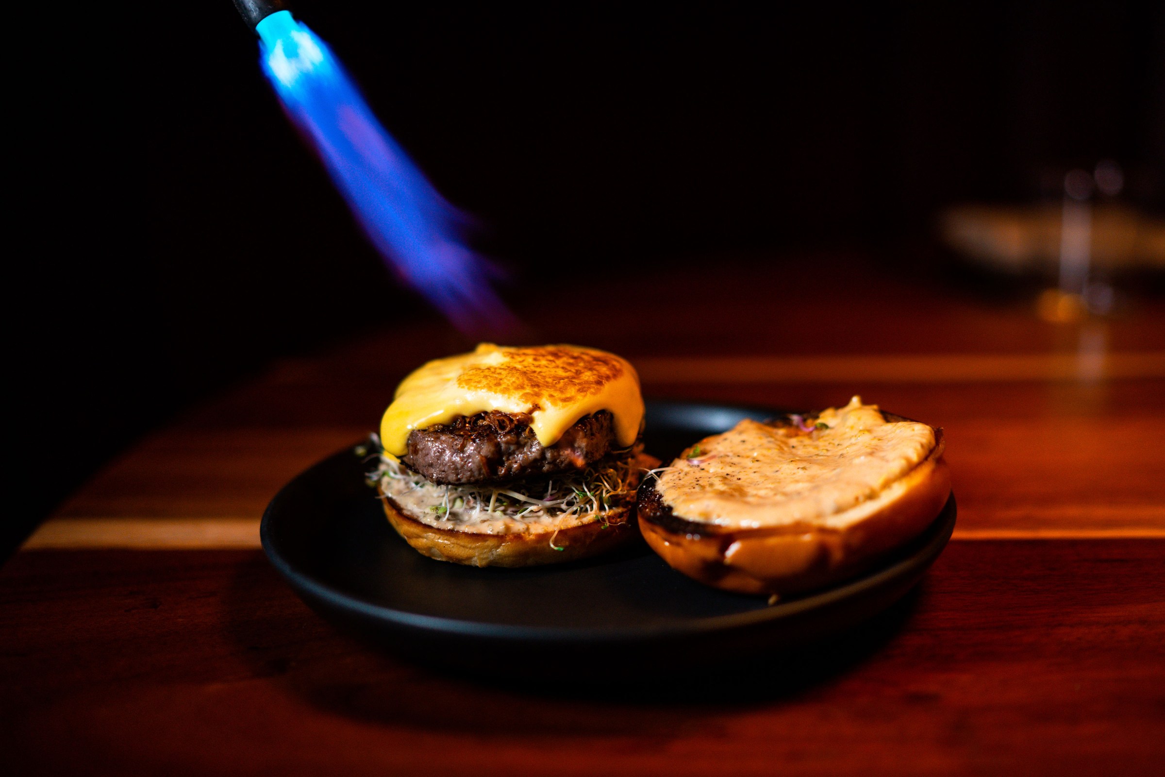 A flame toasts cheese on a burger.