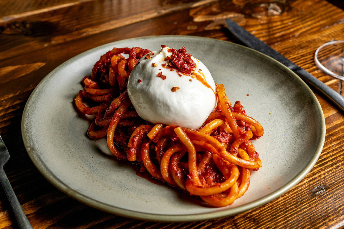 a dish of spicy tomato and nduja bucatini topped with a hefty ball of burrata