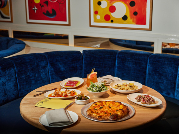 Italian dishes on the table at Pelicano beside velvet blue lounge