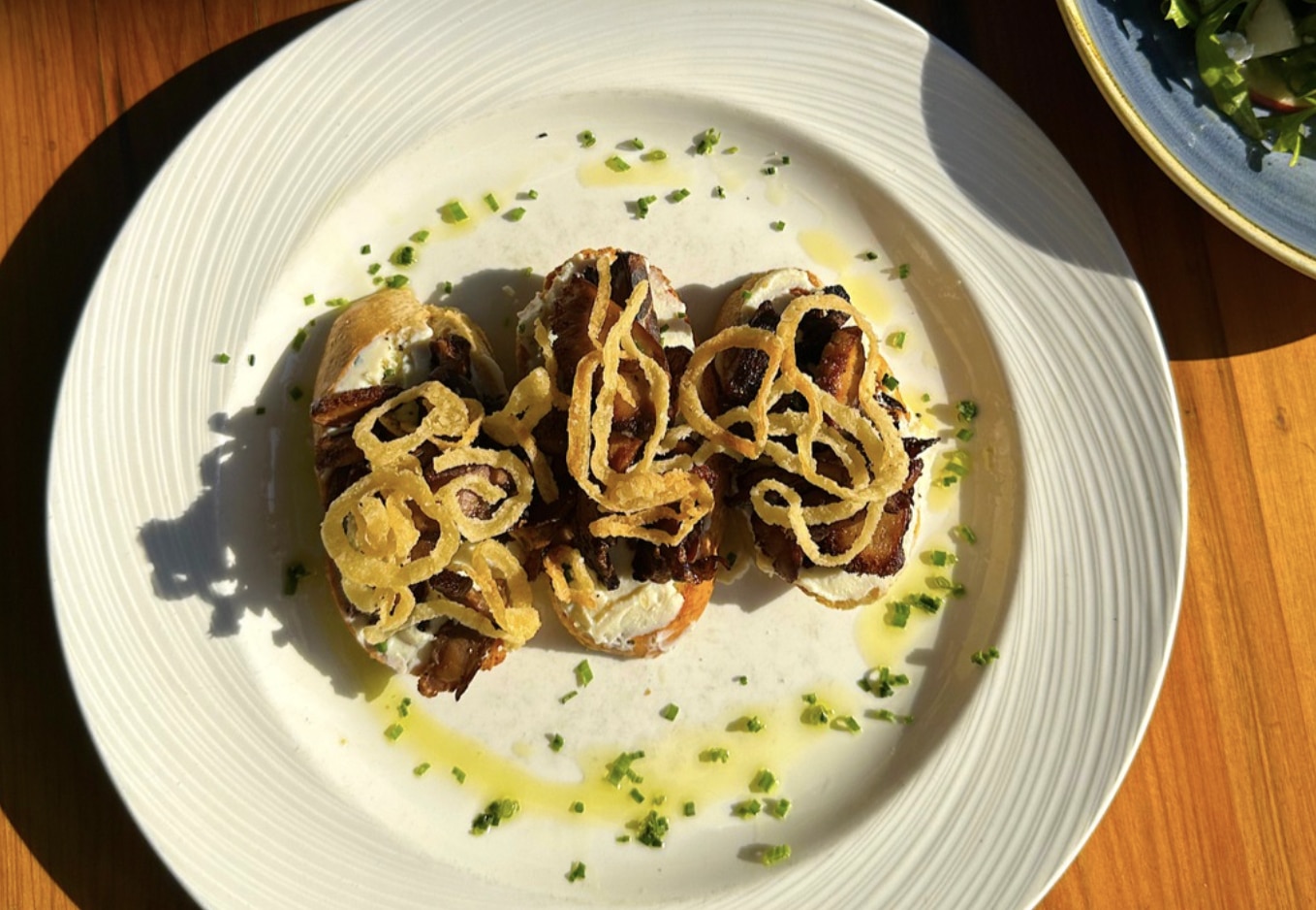 CROSTINI 21 Toasted bread, Lion’s Mane mushrooms, roasted garlic & whipped ricotta, crispy onions, chives from Piccolo Sogno