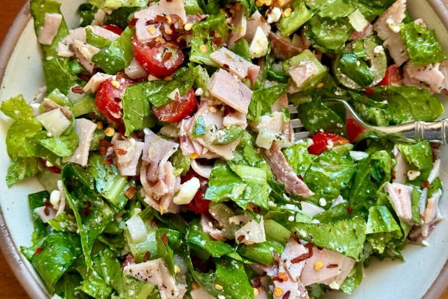 Pizza Shop Salad: The Easy-to-Make Italian Chopped Salad You'll Crave Daily - 2 A fresh salad with crisp lettuce, juicy tomatoes, sliced ham, onions, and creamy feta cheese is just what you need. Tossed with a zesty dressing and finished with a sprinkle of seeds—our shop offers a delightful twist to your usual greens.