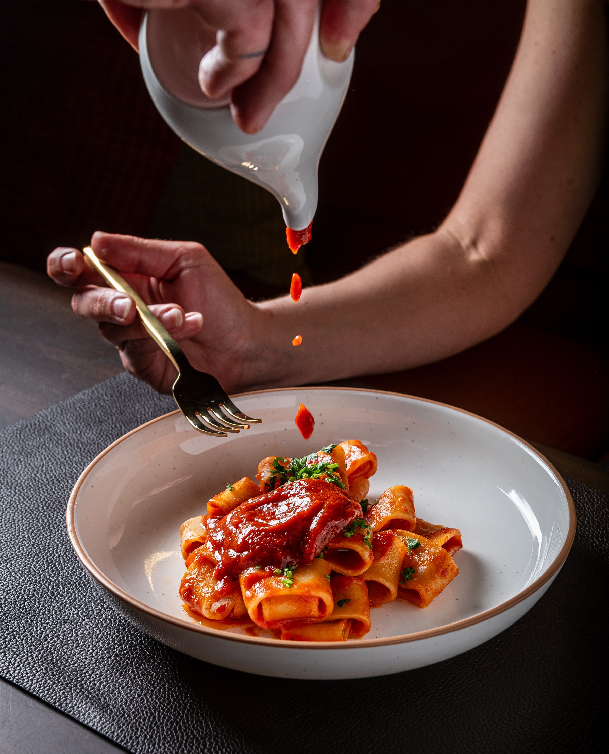 The seven fishes pasta being topped off with more sauce.