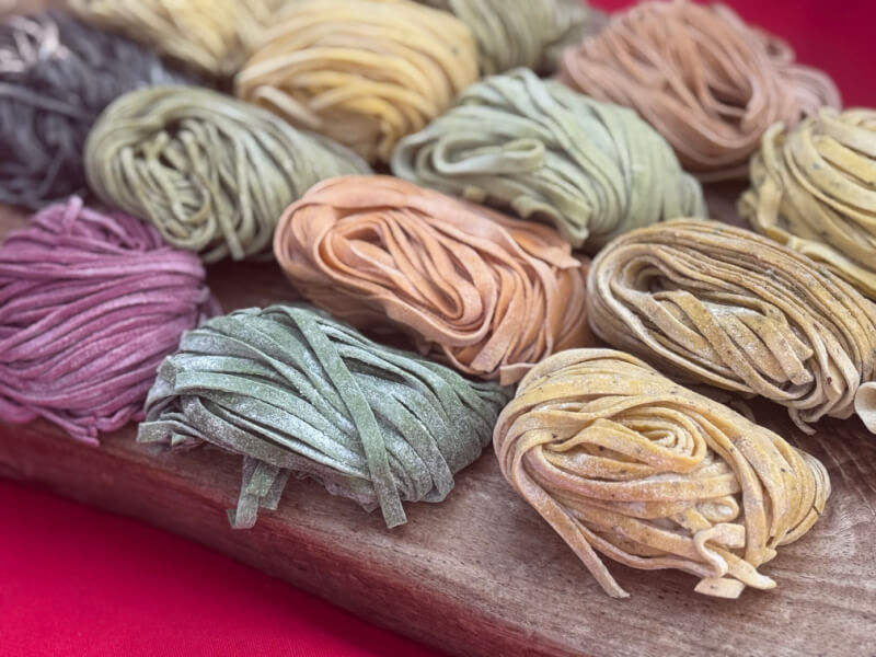 48 Hours in Asheville: A Culinary Tour Through an NC Gem - 15 Assorted bundles of colorful uncooked pasta are arranged on a wooden board, with each bundle displaying a different natural hue.