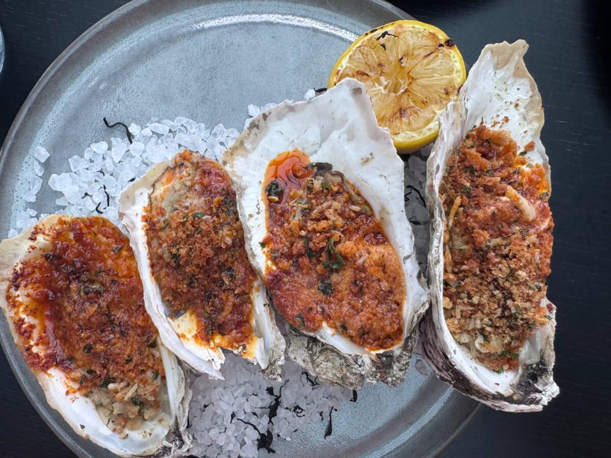 48 Hours in Asheville: A Culinary Tour Through an NC Gem - 4 Four baked oysters topped with a breadcrumb and herb mixture are arranged on a plate with coarse salt, accompanied by a charred lemon half—a coastal favorite featured at top Asheville restaurants.