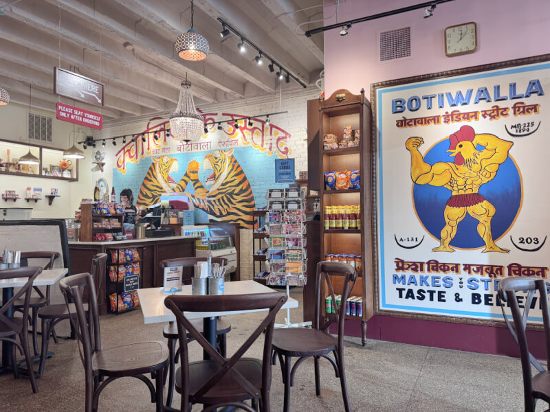 48 Hours in Asheville: A Culinary Tour Through an NC Gem - 8 Interior of a casual Asheville restaurant with Indian-themed decor, featuring colorful murals, a counter area, shelves with snacks, and several empty tables and chairs.