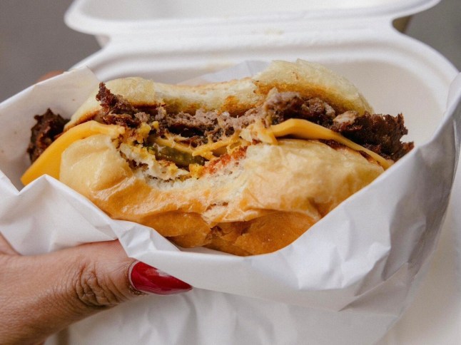 A hand holding a burger from Dumbo
