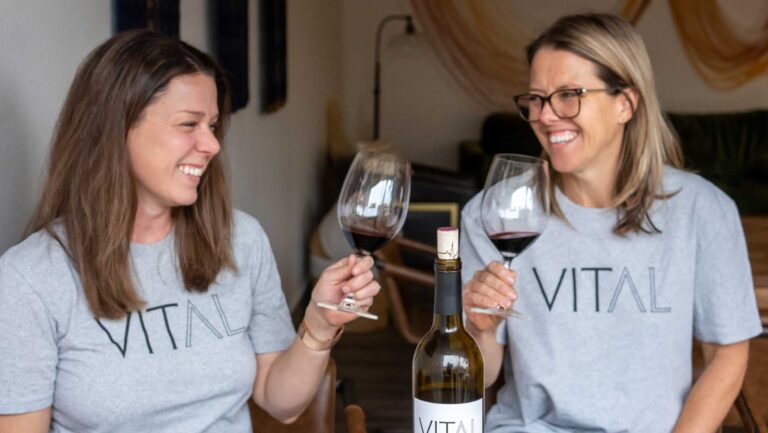 Two women wearing Vital Wines t-shirts and drinking red wine. 