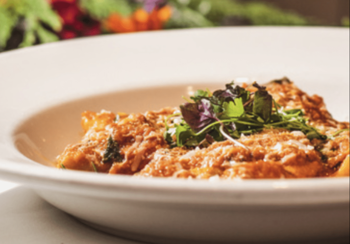 pasta with tomato sauce, parmesan, and garnish in a white bowl from Sapori Trattoria