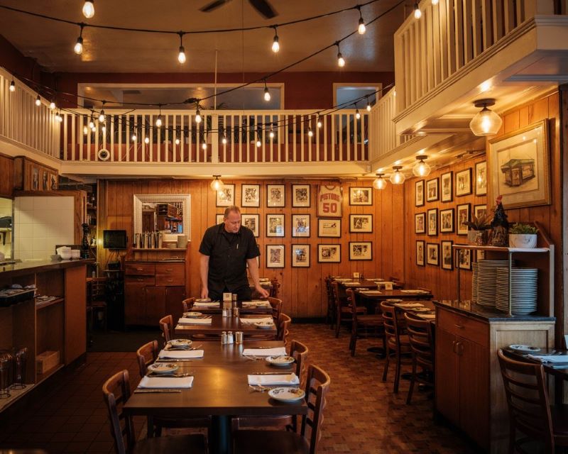 A person sets the table in the dining room at Trattoria Contadina