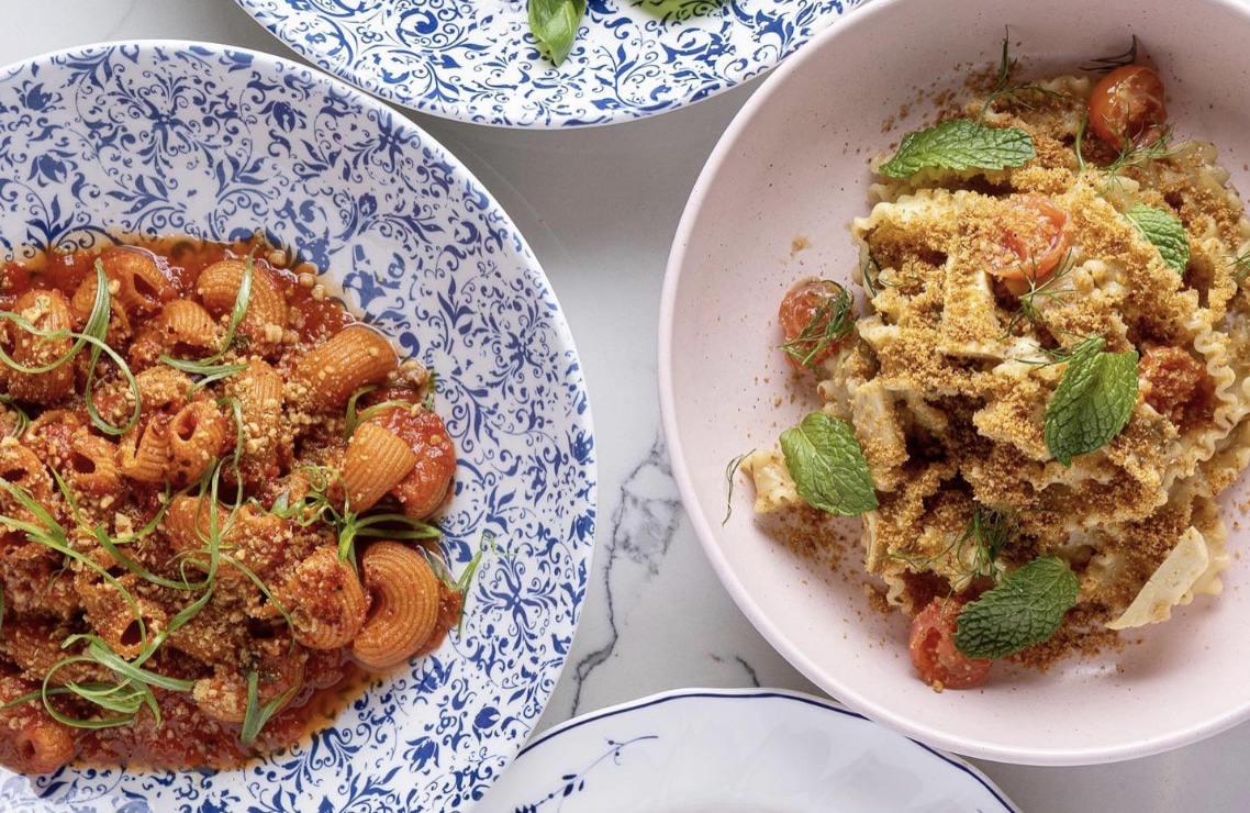 two pasta dishes with tomato sauce and tomatoes and garnishes from Adalina in Chicago