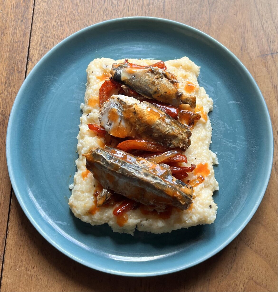 Sardines in hot sauce, with onions and peppers on a bed of grits.