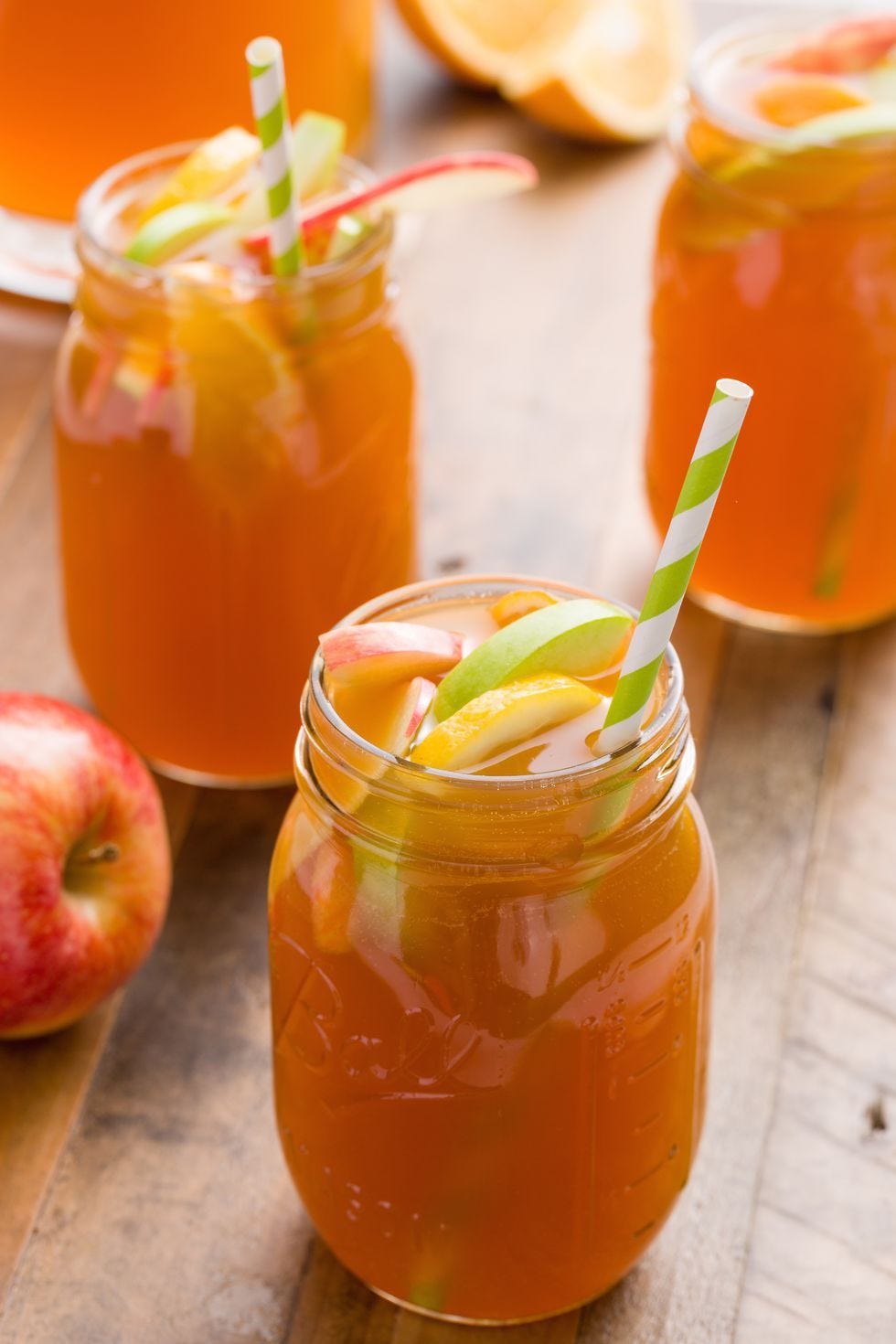 a glass of apple cider sangria with a green straw poking out