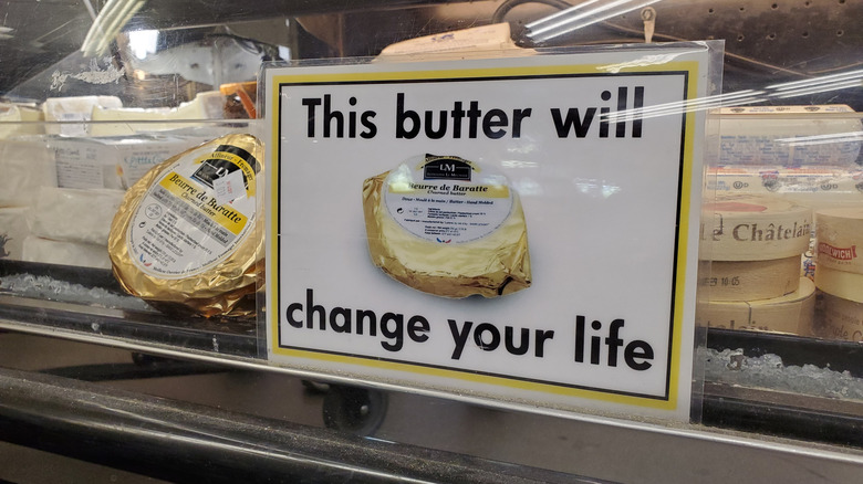 A round package of Beurre de Baratte next to a sign with the words 