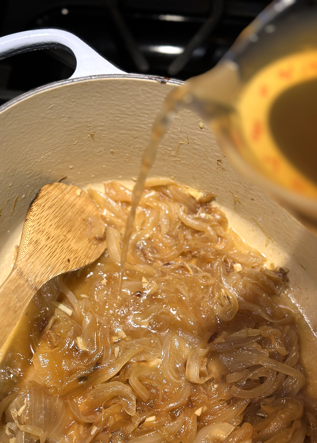 mushroom stock pouring into onion soup pot