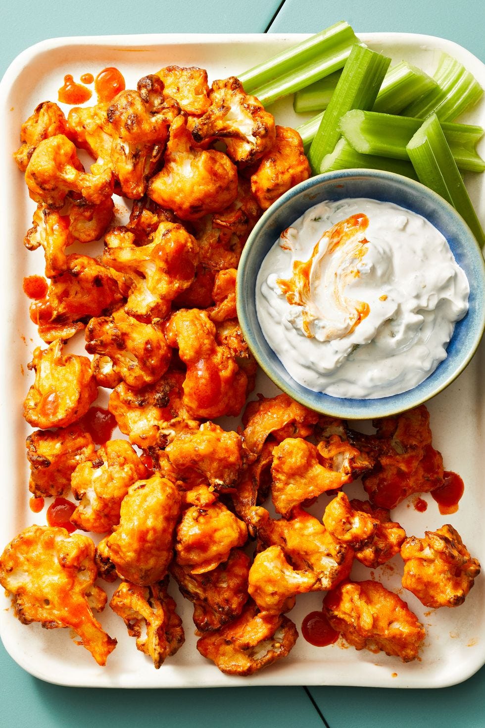 buffalo cauliflower wings with dipping sauce and celery on the side italian marinated chicken over a bed of salad