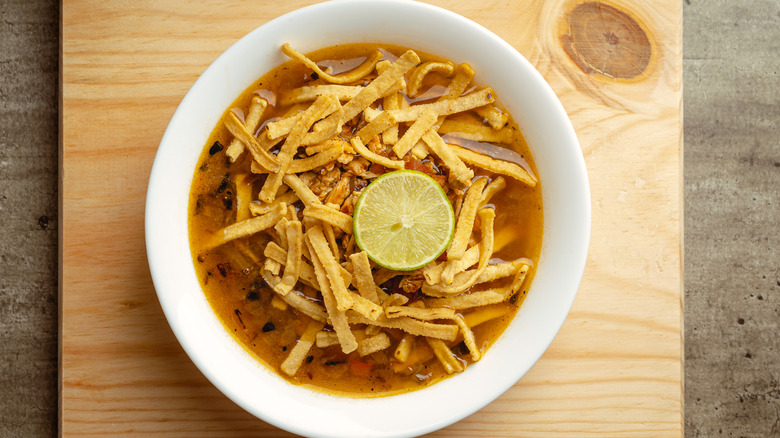 A plate of traditional lime soup from the state of Yucatan, on a wooden table