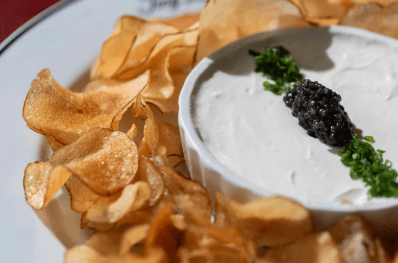 Potato chips surround a white bowl of french onion dip topped with black caviar at Tiny Lou's in Atlanta. 