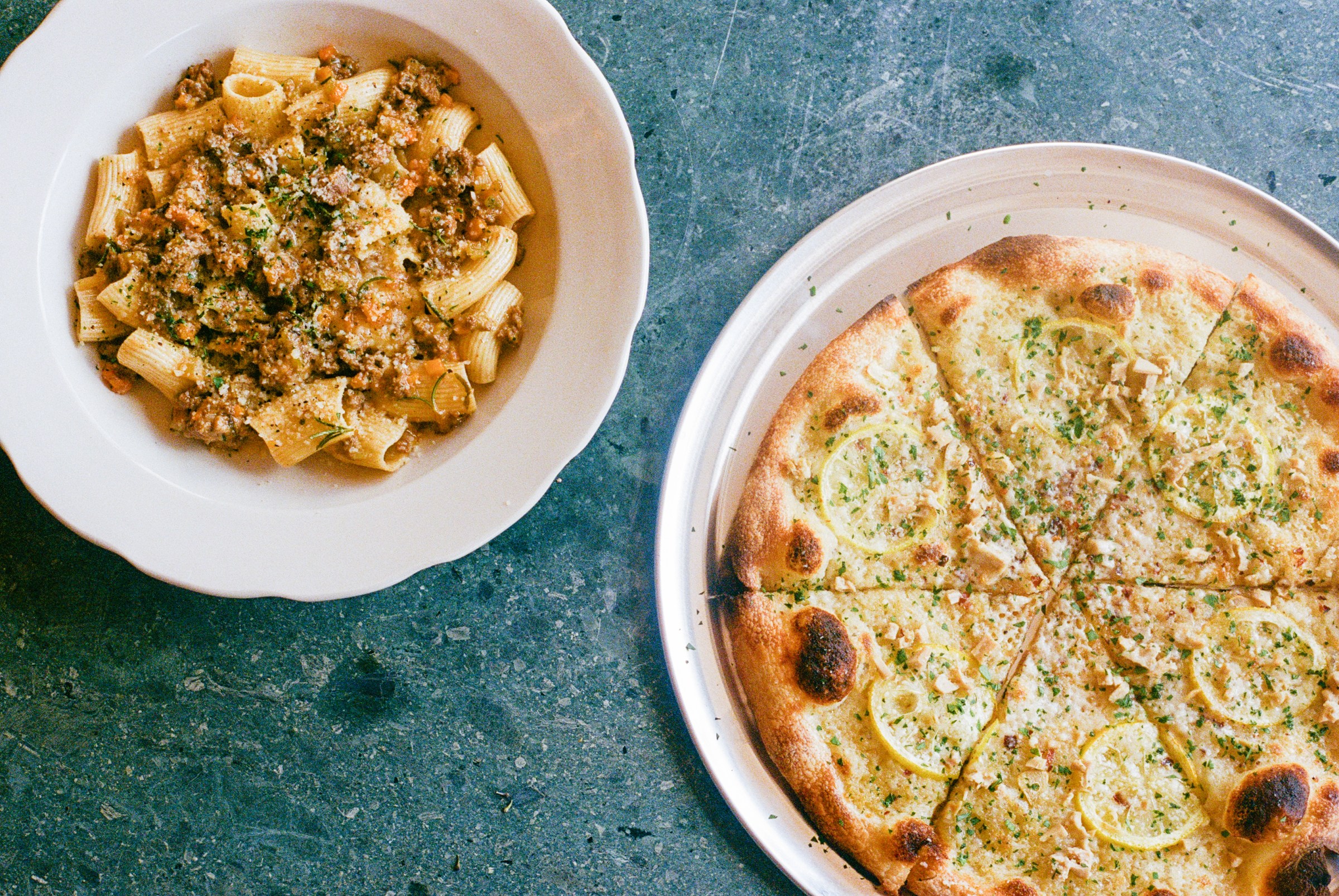 Overhead shot of clam pizza and rigatoni Bolognese on film.