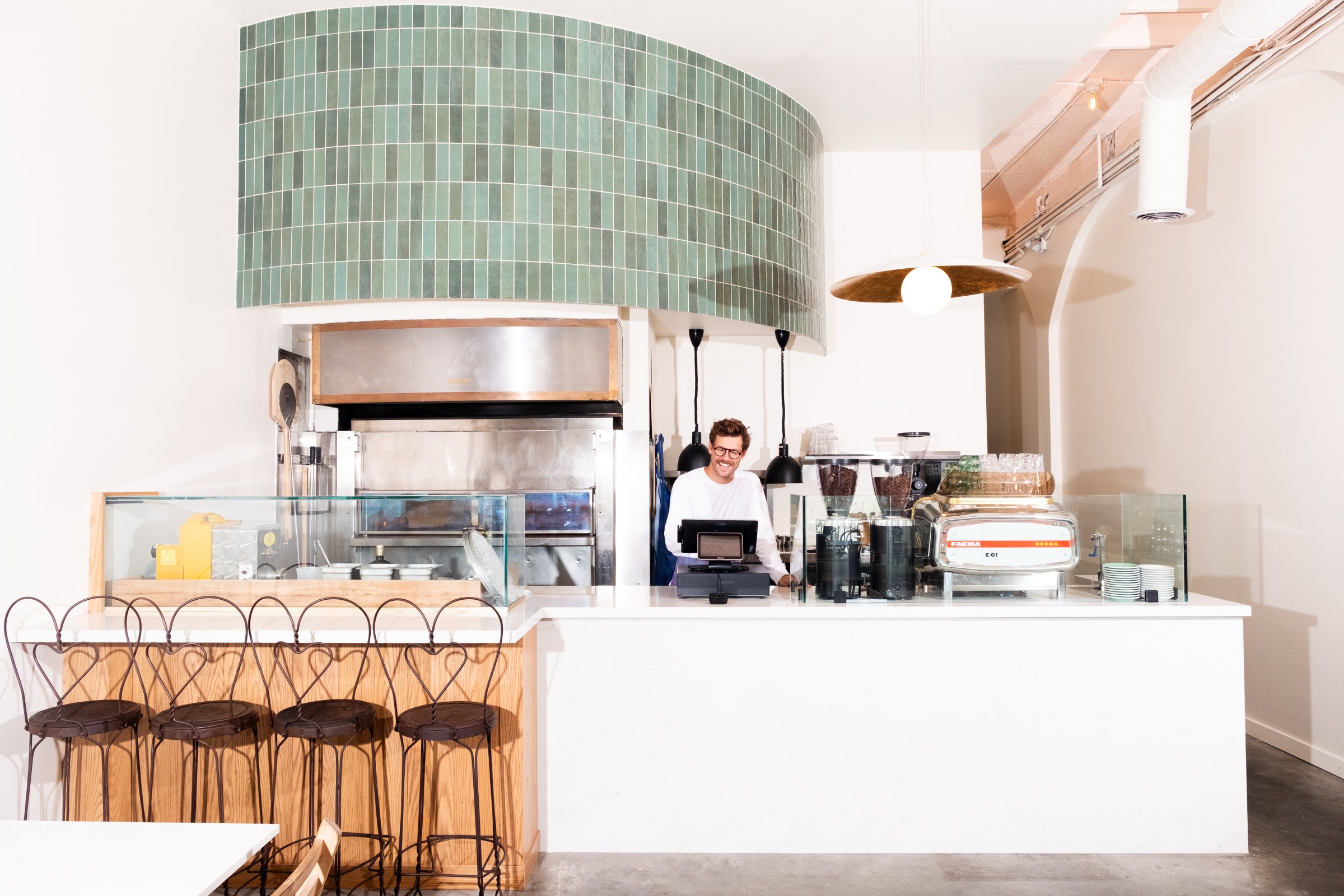 Front counter of Companion with green subway tile overhead and a short bar for seating in Venice, California.