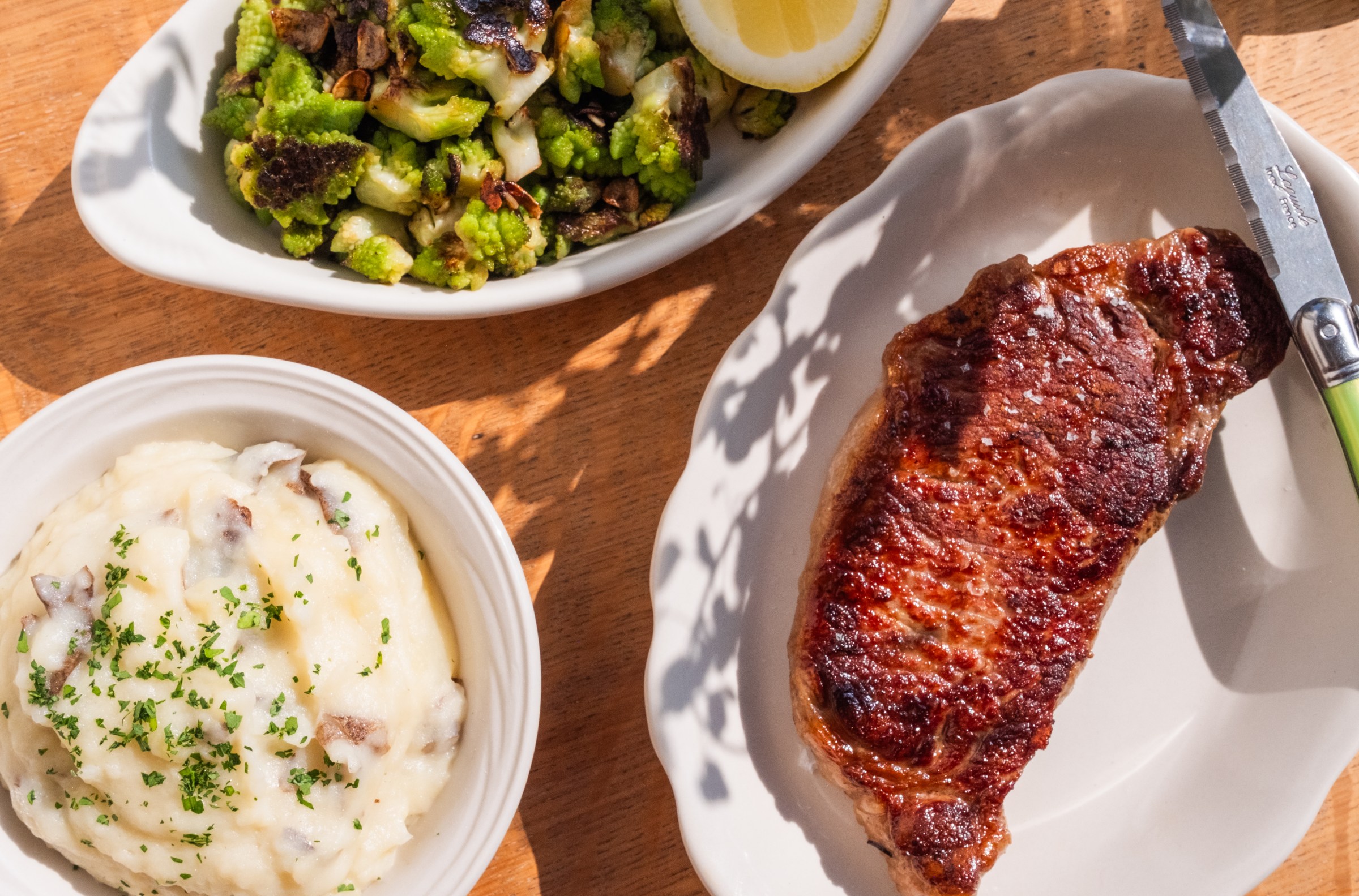 Overhead shot of a New York strip with mashed potato and grilled Romanesco on the site