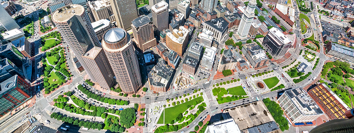 An aerial view shows the Rose Kennedy Greenway snaking through tall buildings of Downtown Boston