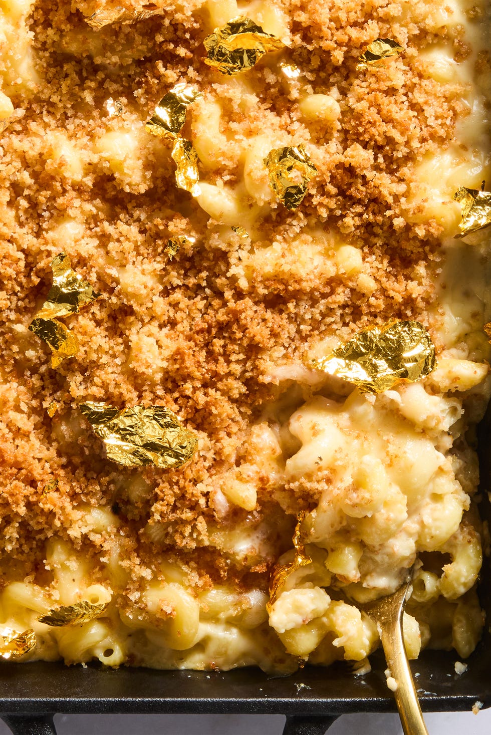 million dollar mac and cheese topped with panko breadcrumbs and gold leaf in a cast iron pan