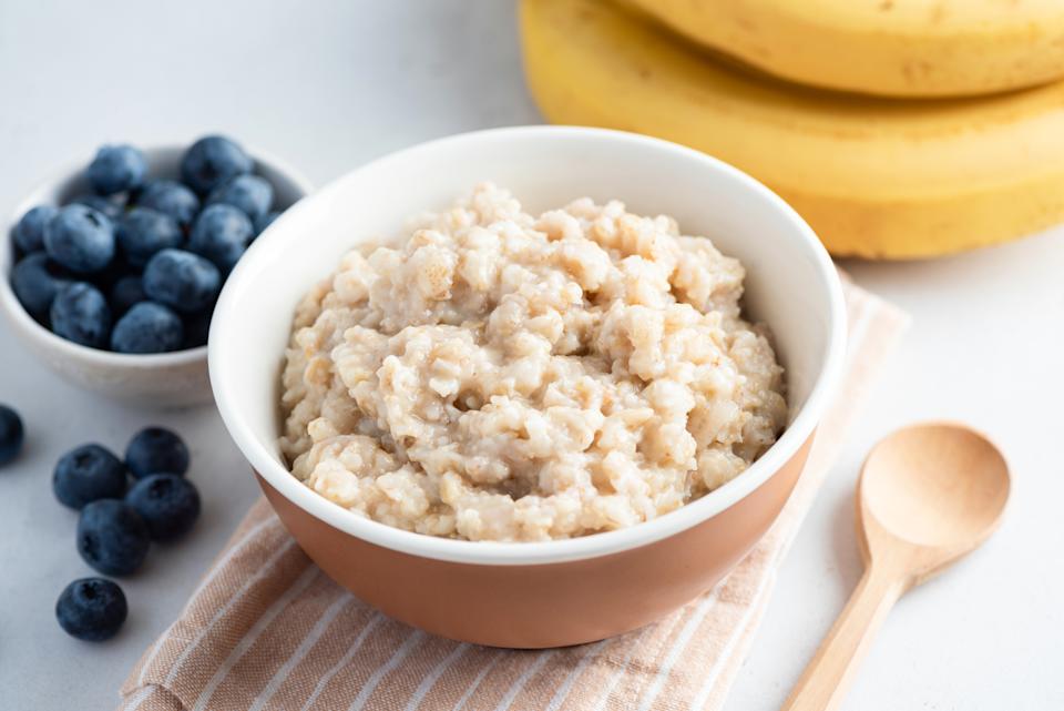 Simple Oatmeal porridge in bowl served with blueberries and banana. Healthy vegan wholesome breakfast in a bowl