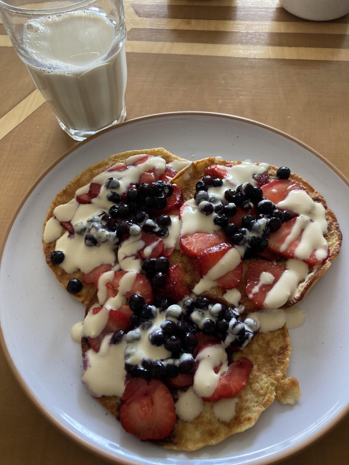 Whole oat pancakes with berries and a yogurt-maple drizzle, soy milk on the side