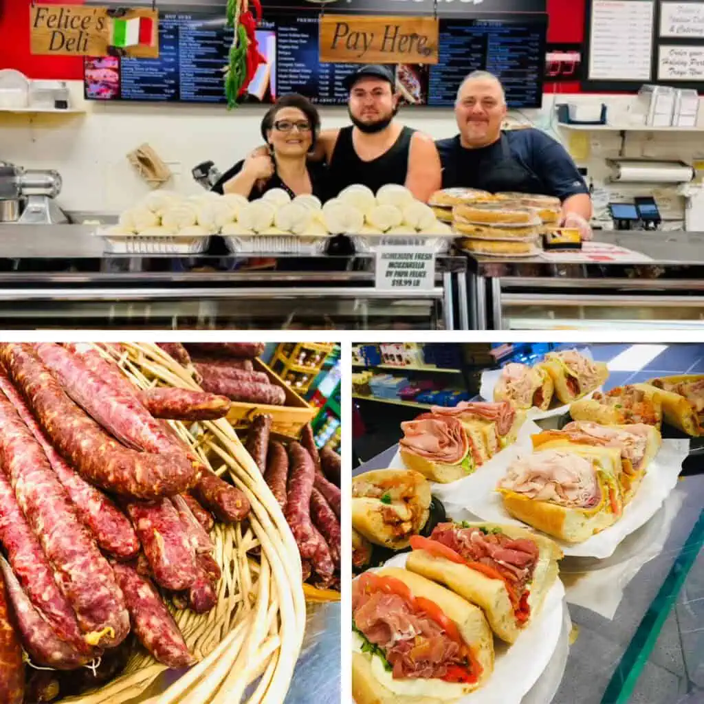 Three people are posing behind a deli counter. A basket of sausages. Six sub sandwiches on plates.
