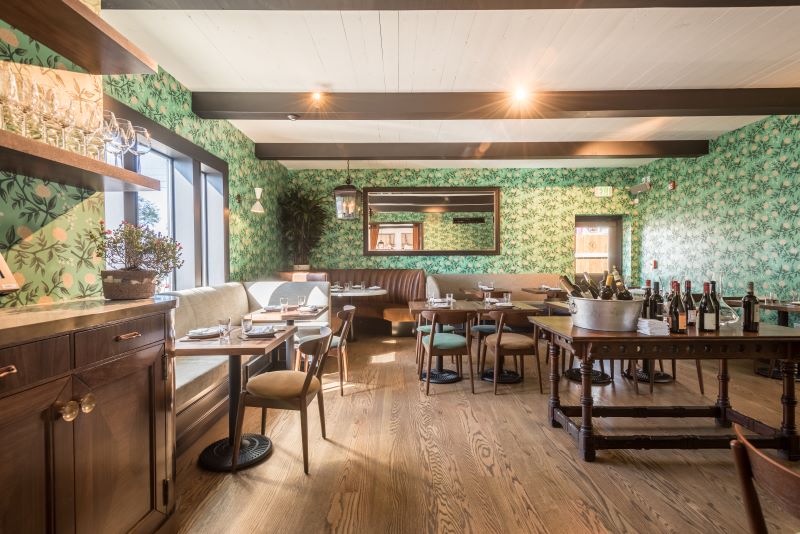 Dining room with green patterned wallpaper and exposed dark wood beams at Felix.