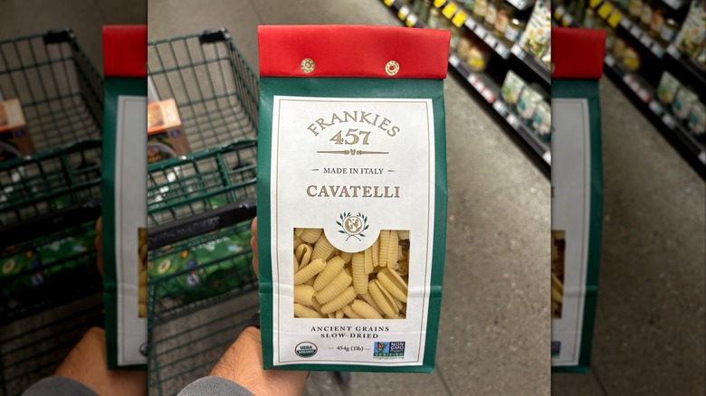 Hand holding a green, red, and white bag of cavatelli pasta
