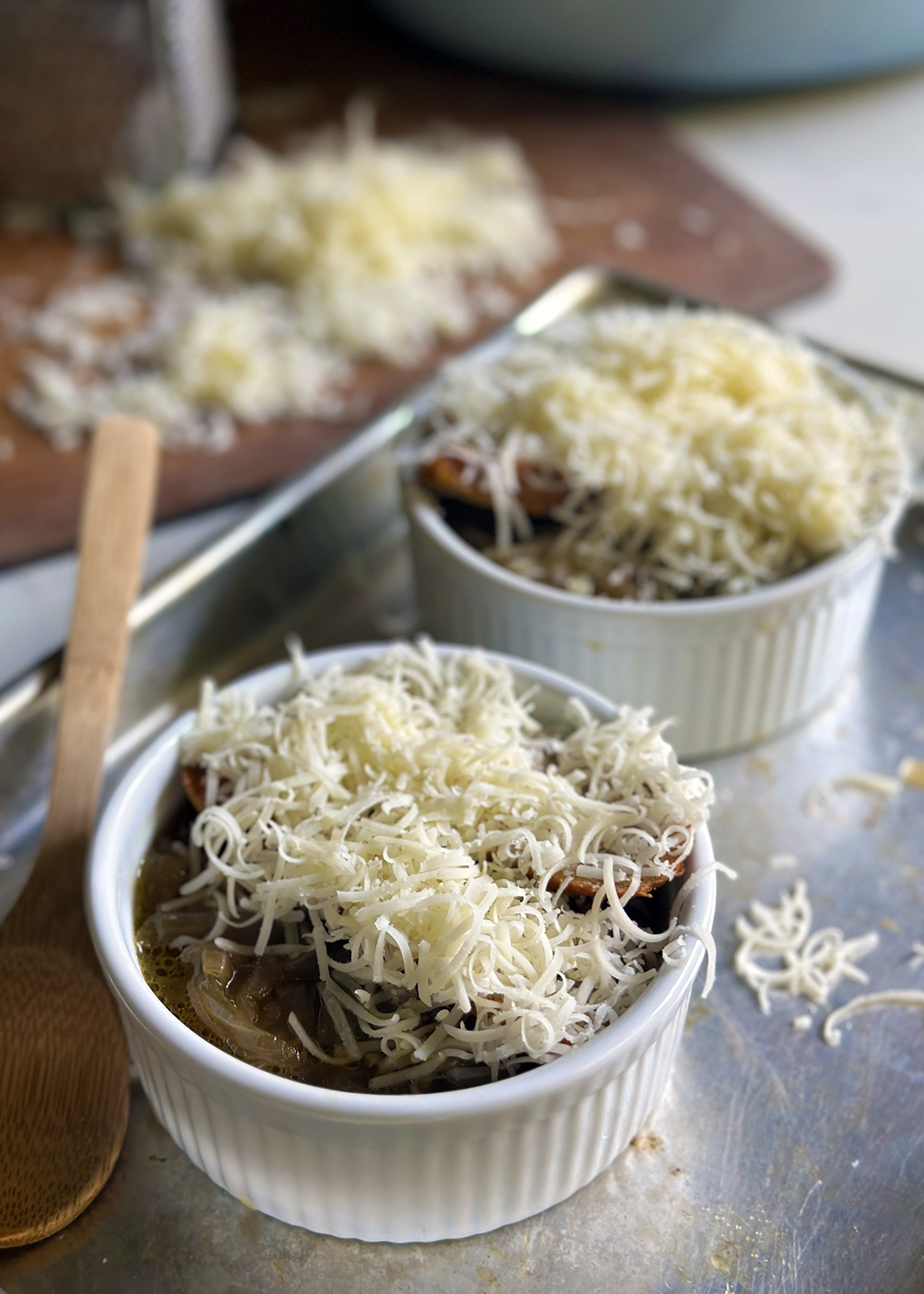 french onion soup in ramekins covered with shredded cheese
