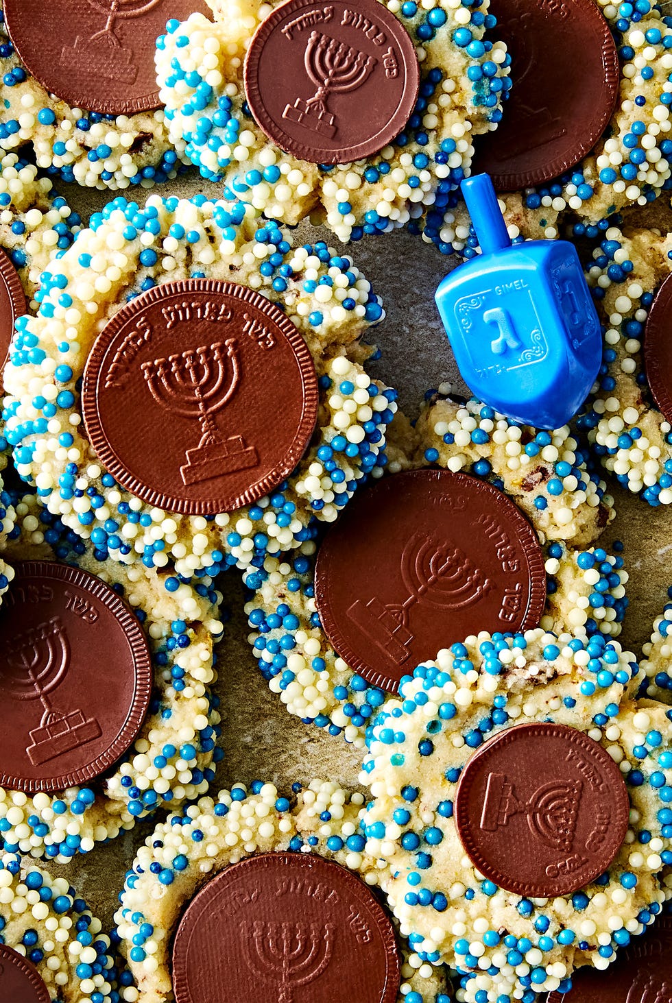 thumbprint cookies with blue and white sprinkles with a chocolate gelt coin in the center
