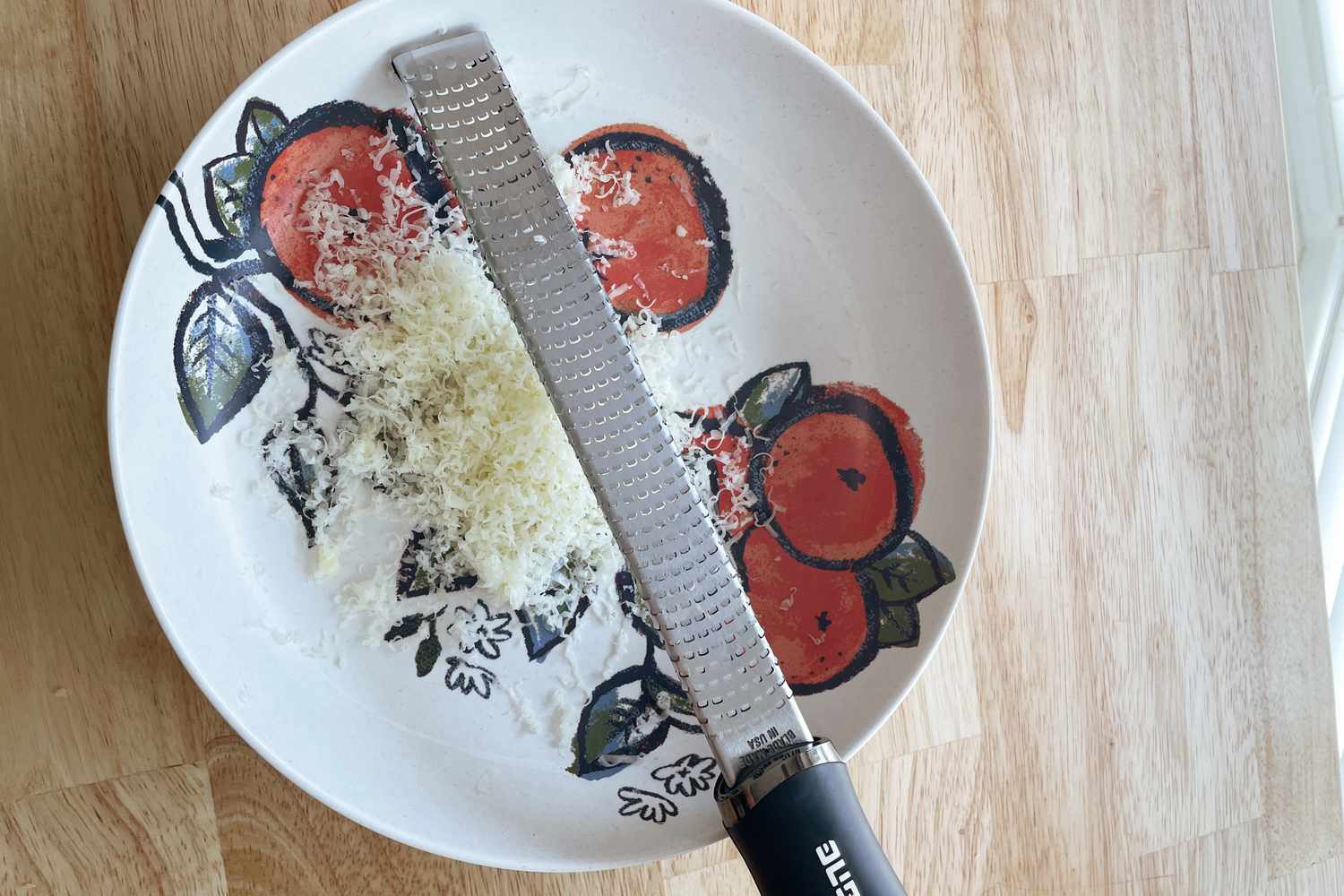Microplane Premium Zester displayed on a colorful plate on a wooden surface