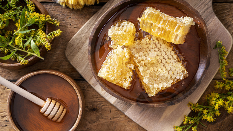 Raw honeycomb and honey on wooden table