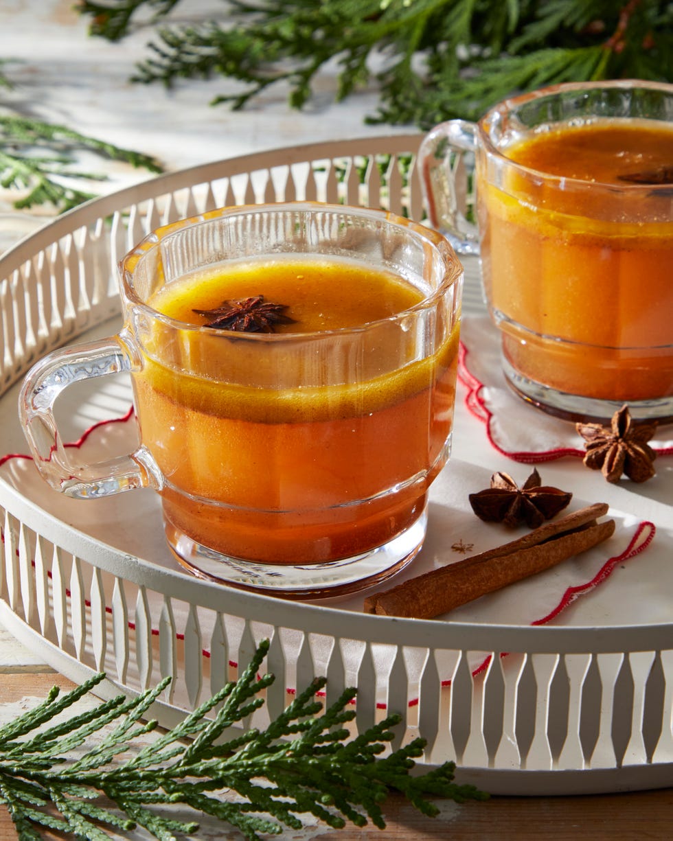 hot spiced beverage served in glass mugs on a white tray with spices