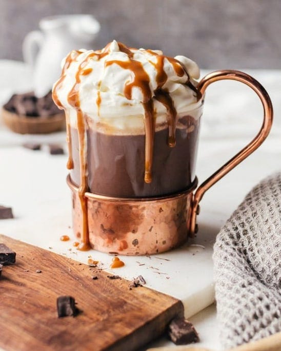 bourbon hot chocolate with whipped cream and caramel sauce in copper glass mug