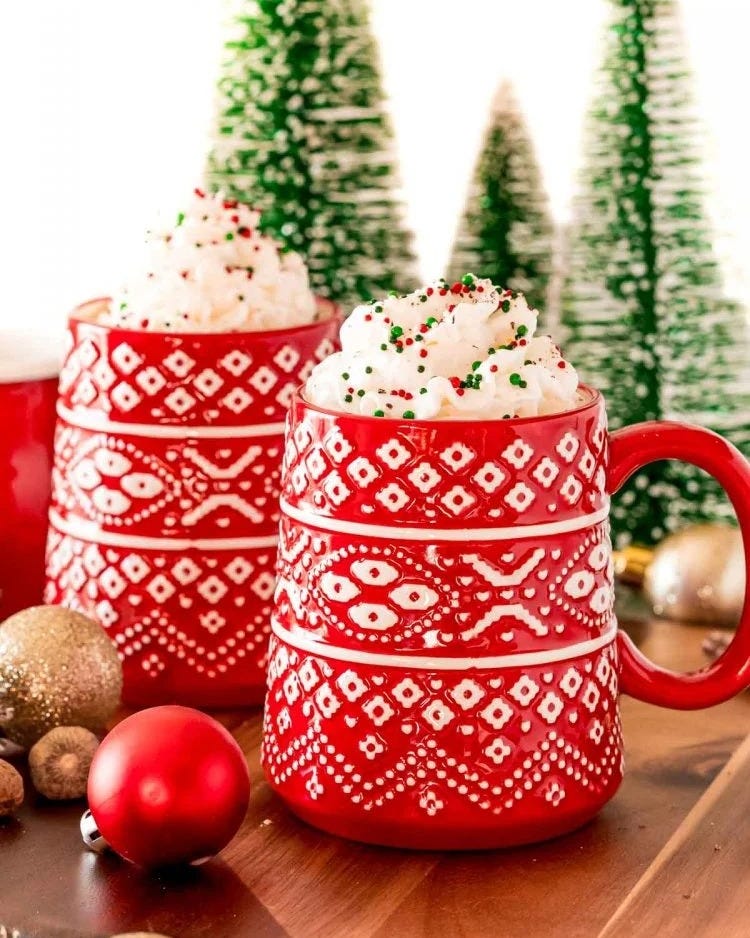 eggnog hot chocolate in red mugs with whipped cream