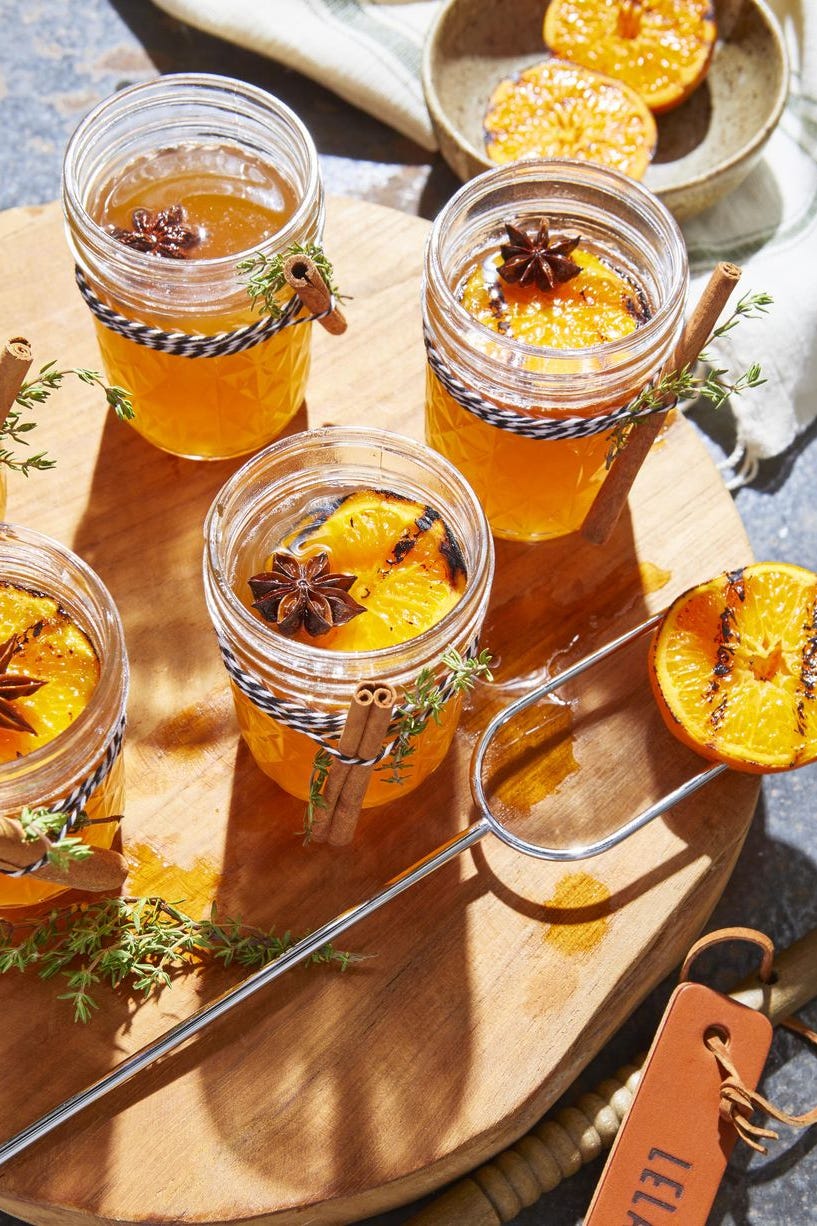 hot toddies with charred oranges on a wooden board